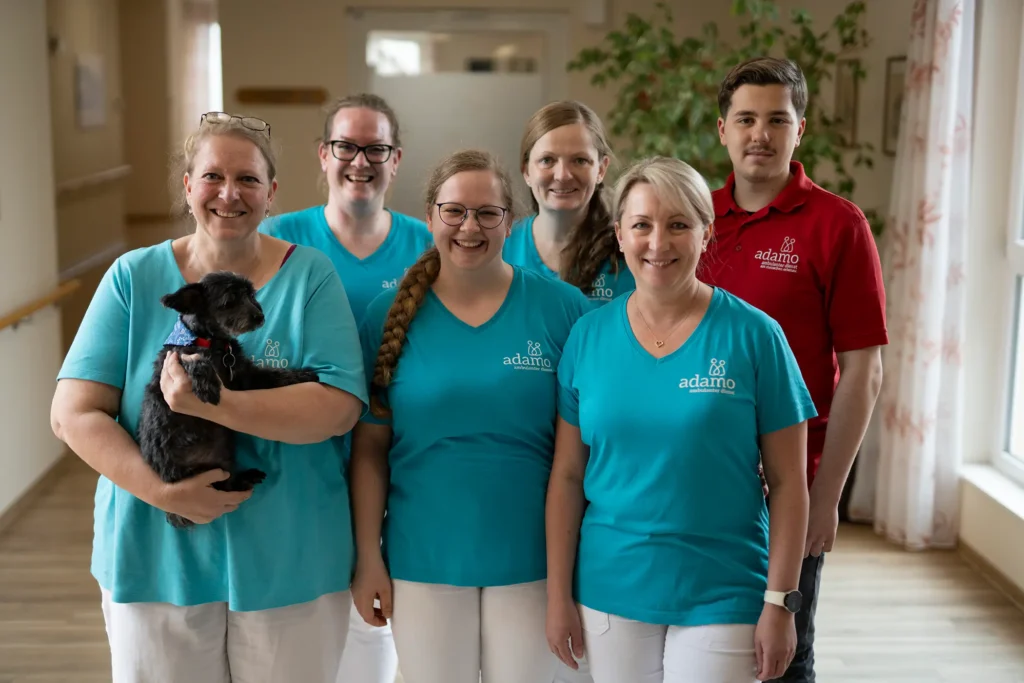 Das Pflegeteam von adamo lächelt in die Kamera – Mitarbeiterinnen und Mitarbeiter des ambulanten Dienstes am Menschen.